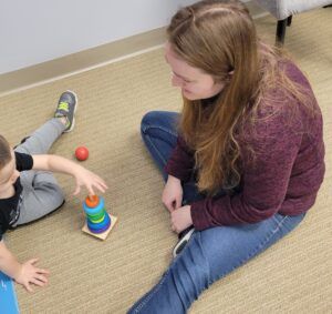 A woman is sitting on the floor playing with a child.