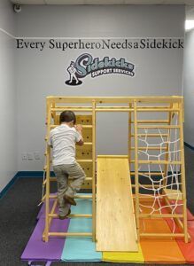 A child climbs a wooden ladder in front of a sign that says
