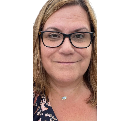 A woman wearing glasses and a necklace is smiling for the camera.