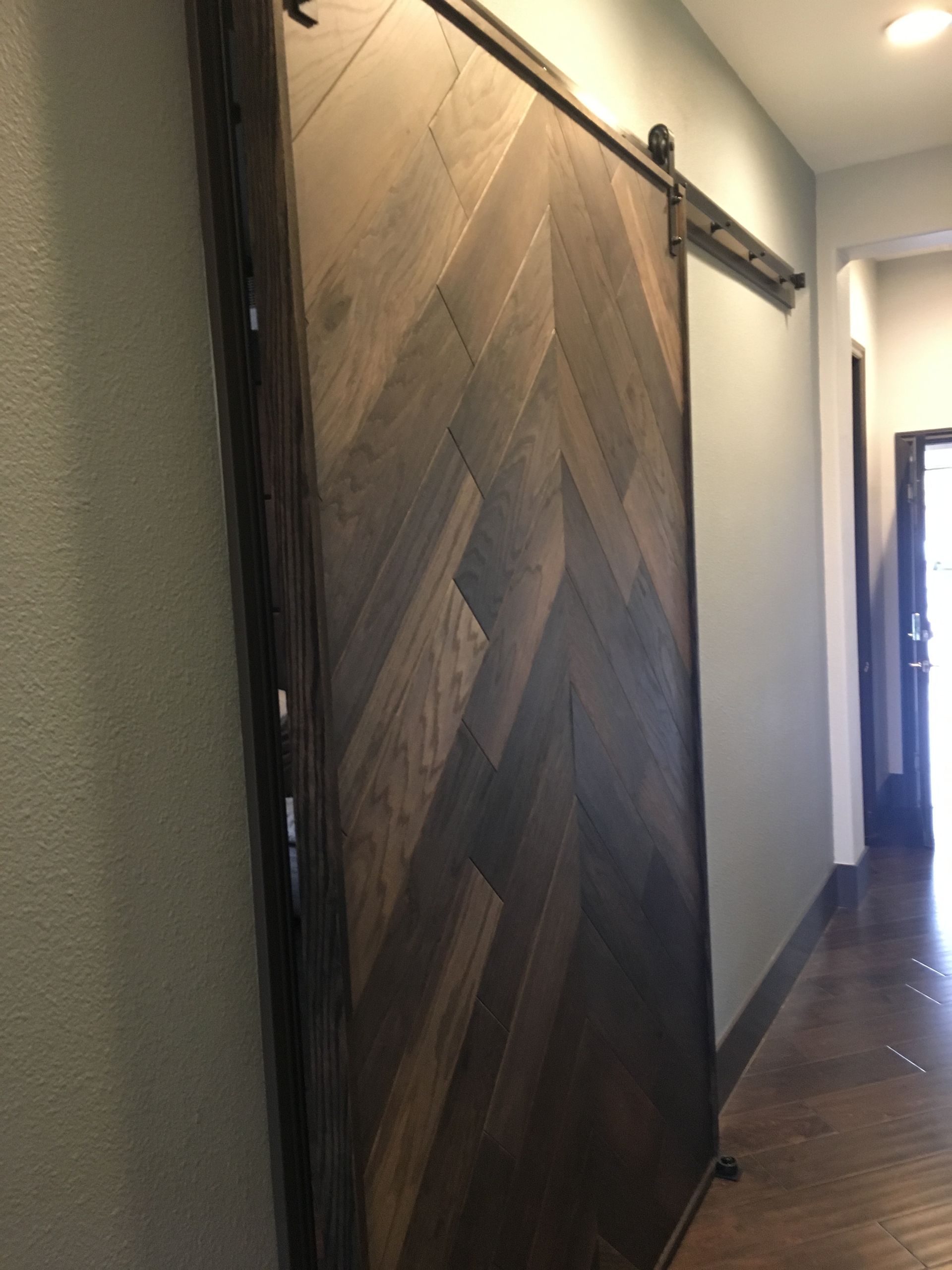 Wooden barn door in a narrow hallway, partially open on a sliding track.