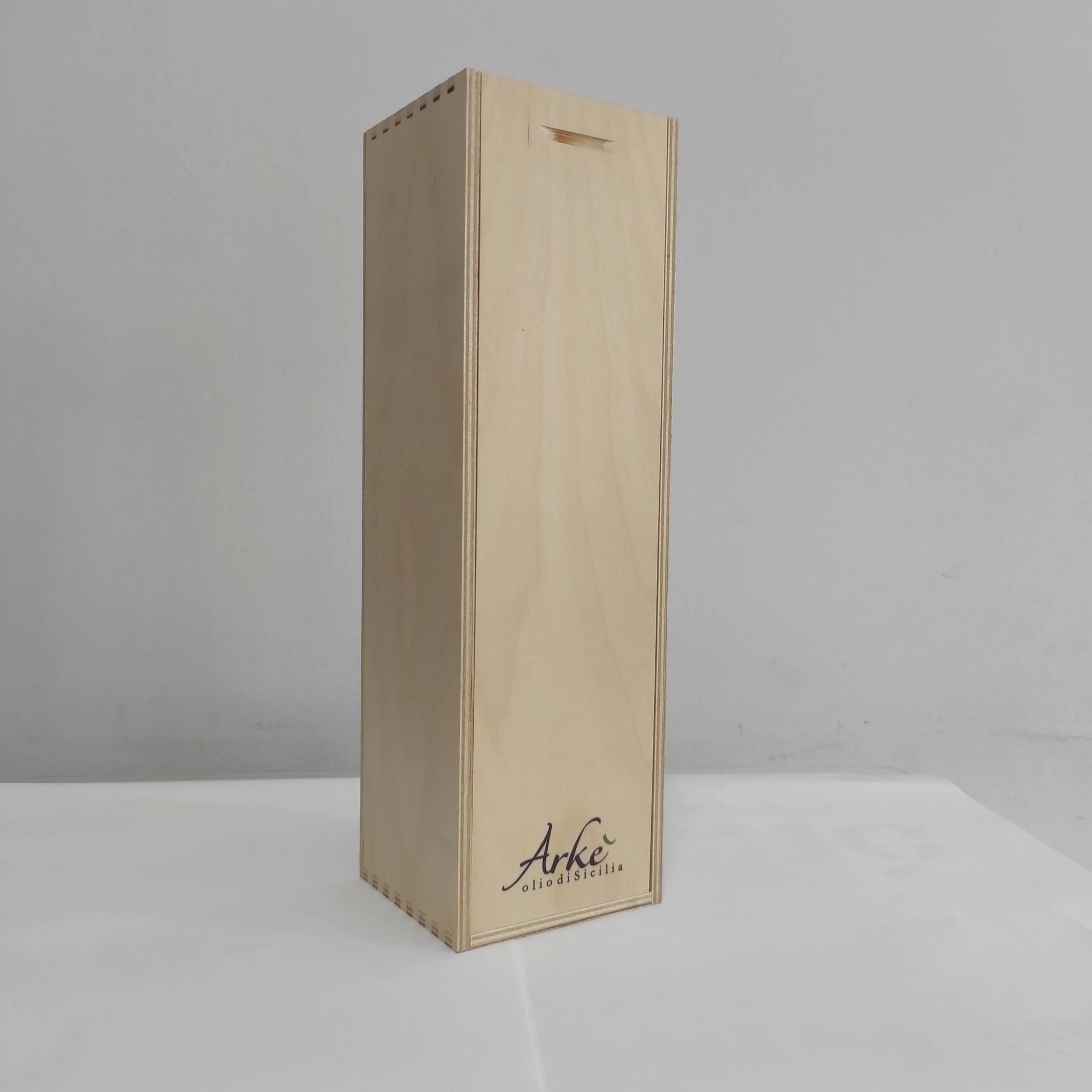 Elegante scatola regalo alta in legno chiaro con un piccolo logo nero su sfondo grigio uniforme.