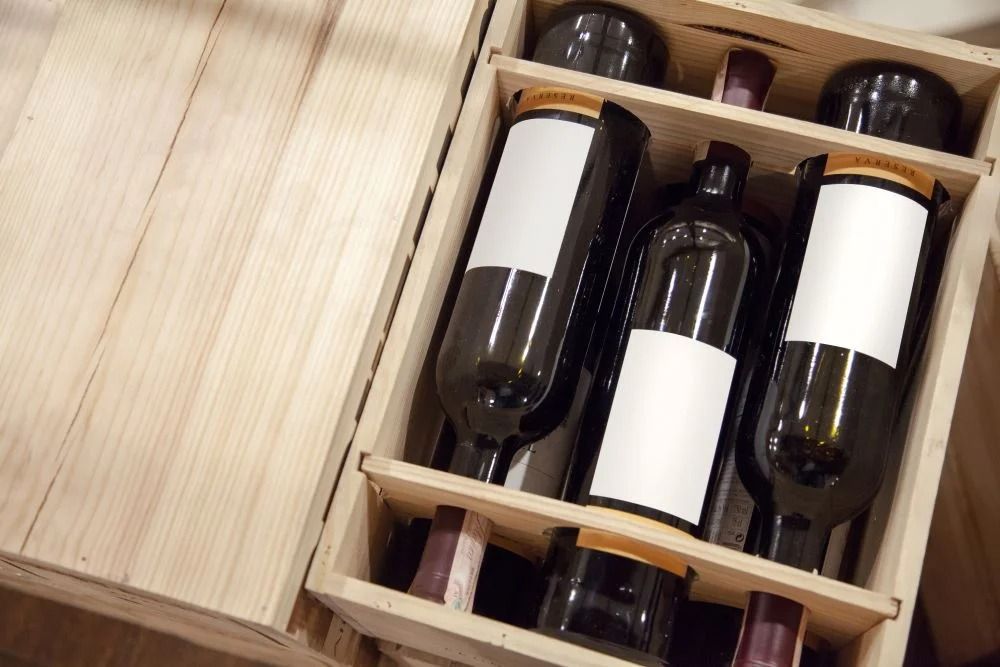 Cassa di legno per vino contenente diverse bottiglie con etichette bianche vuote in una scatola di stoccaggio