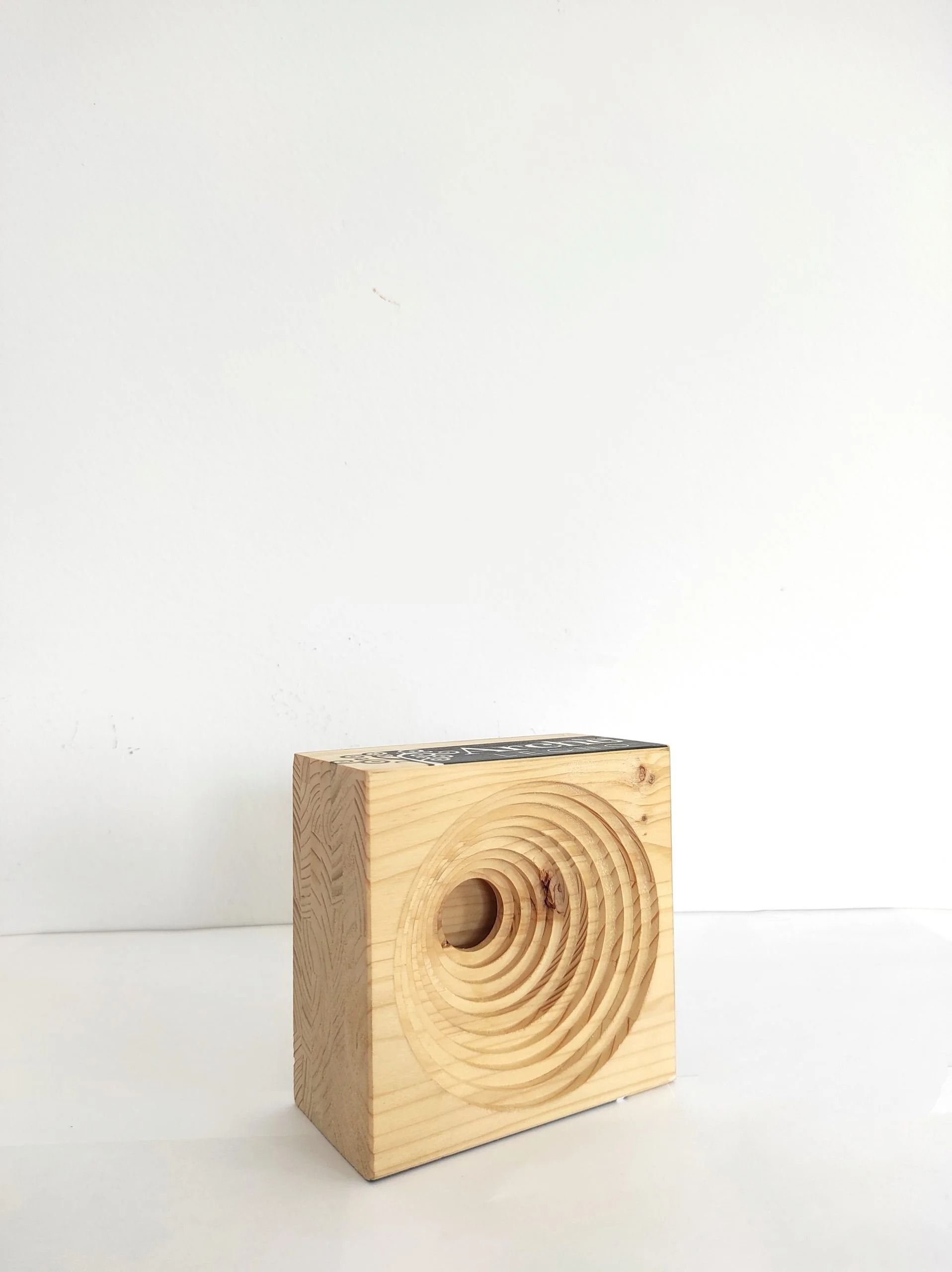 Blocco di legno con scanalature concentriche intagliate su sfondo bianco