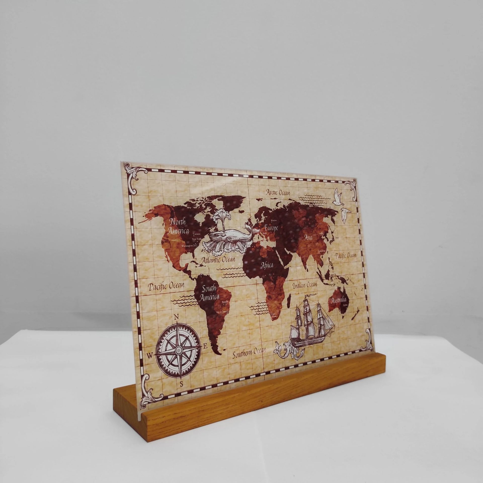 Targa con mappa del mondo vintage su supporto in legno, su sfondo neutro.