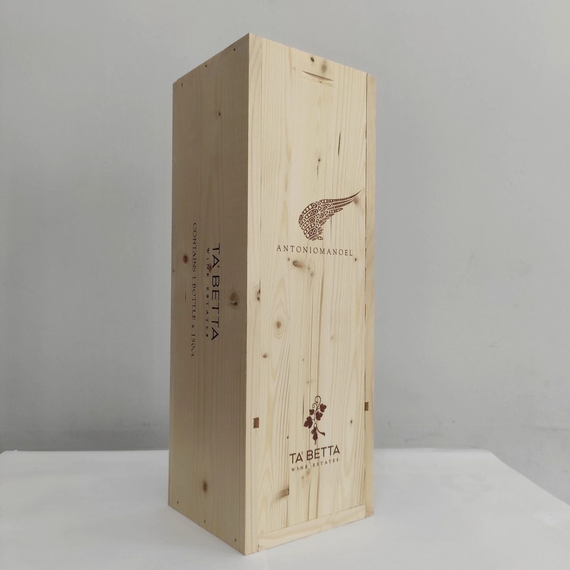 Cassa di legno per vino in posizione verticale su una superficie bianca, contro uno sfondo grigio uniforme.