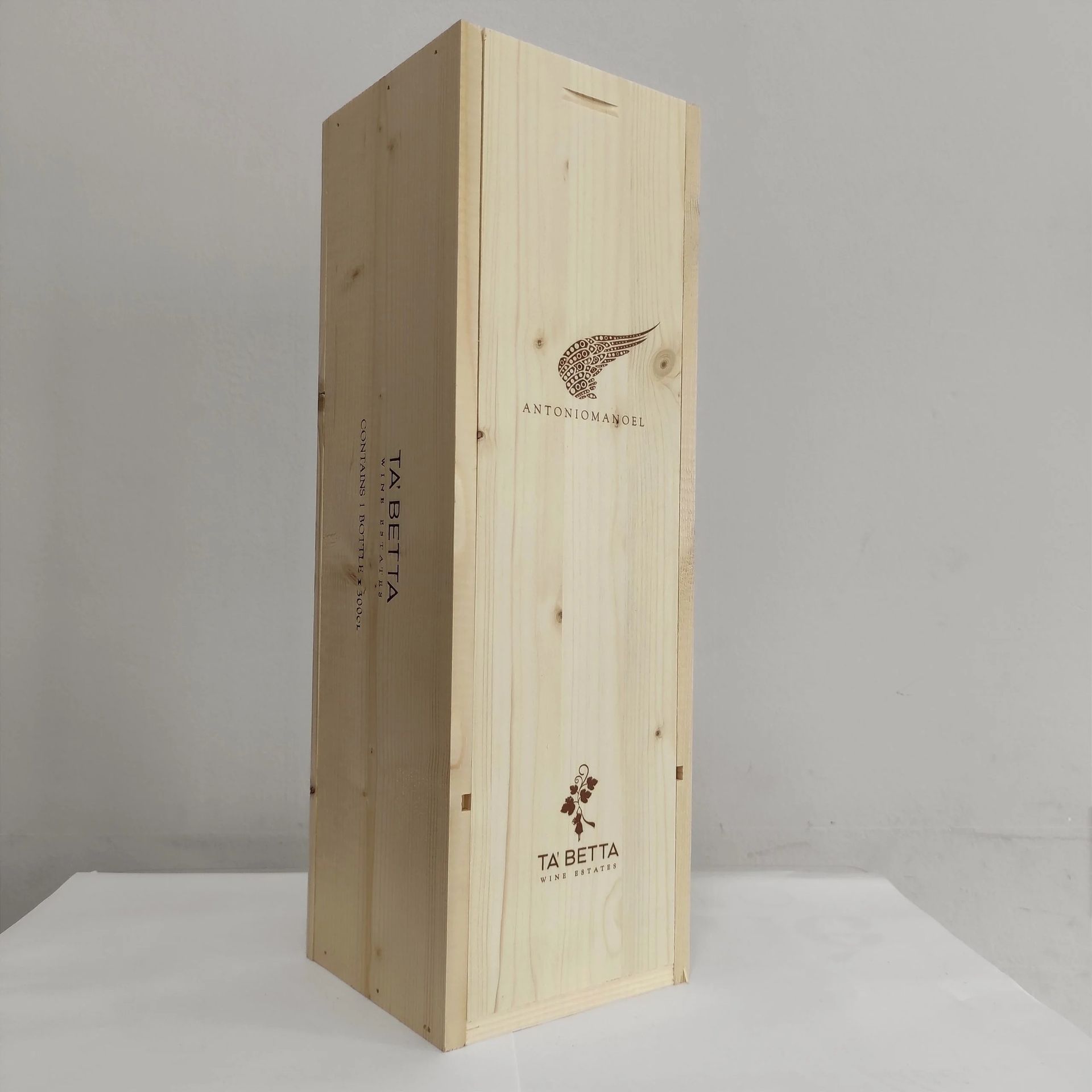 Scatola di legno alta e non rifinita, appoggiata su una superficie bianca su sfondo grigio.