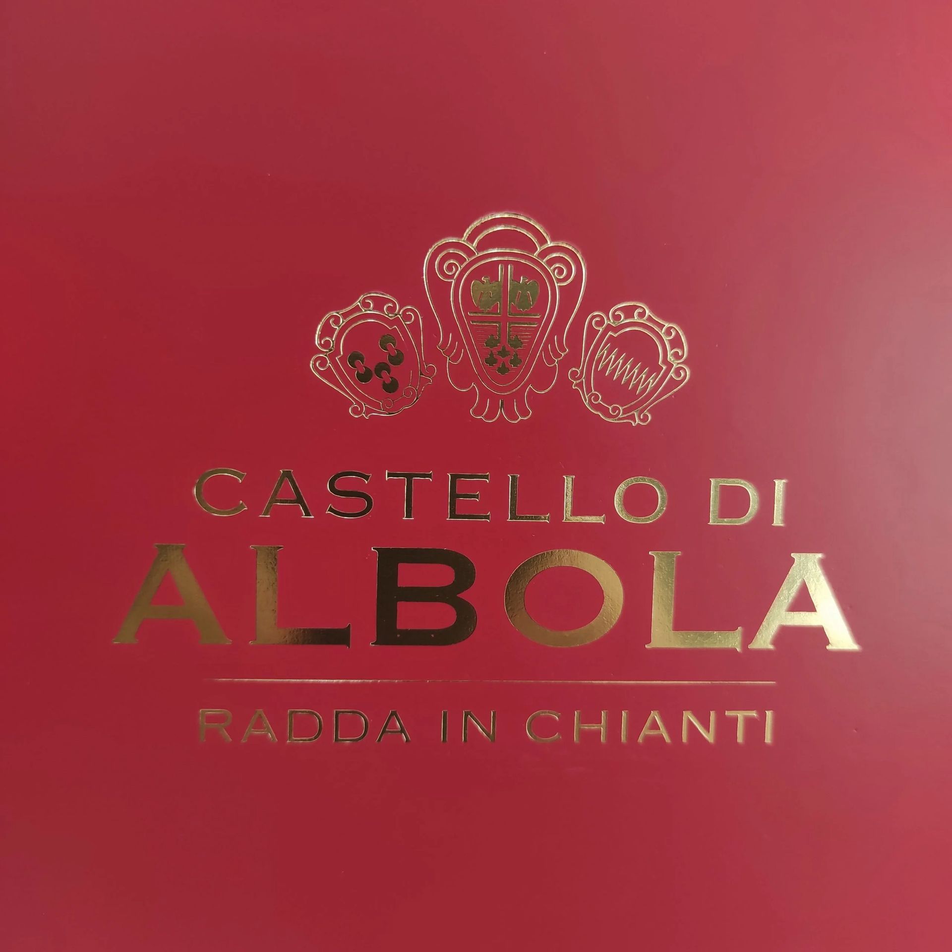 Sfondo rosso con logo e testo dorati “Castello di Albola, Radda in Chianti”