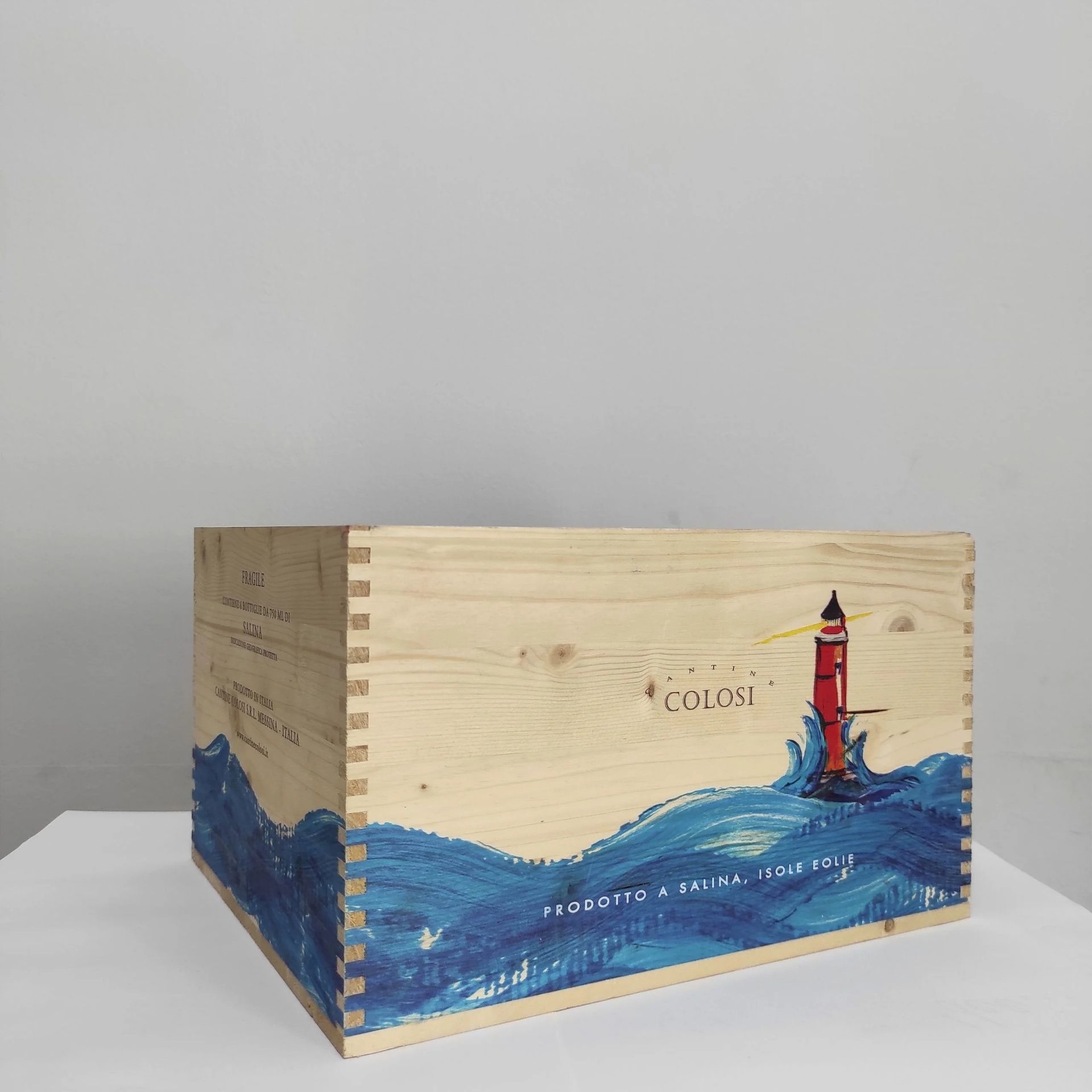 Cassa di legno con un'onda blu dipinta e un faro rosso su sfondo grigio chiaro