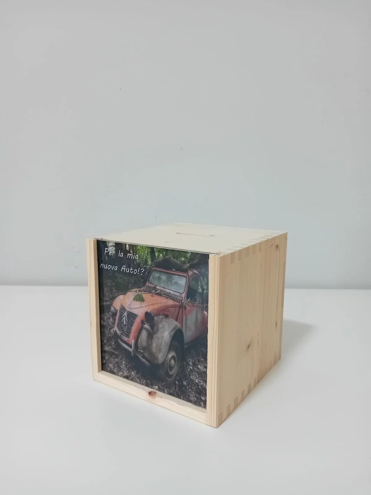 Scatola cubica in legno con la foto frontale di un veicolo rosso in un ambiente boschivo.