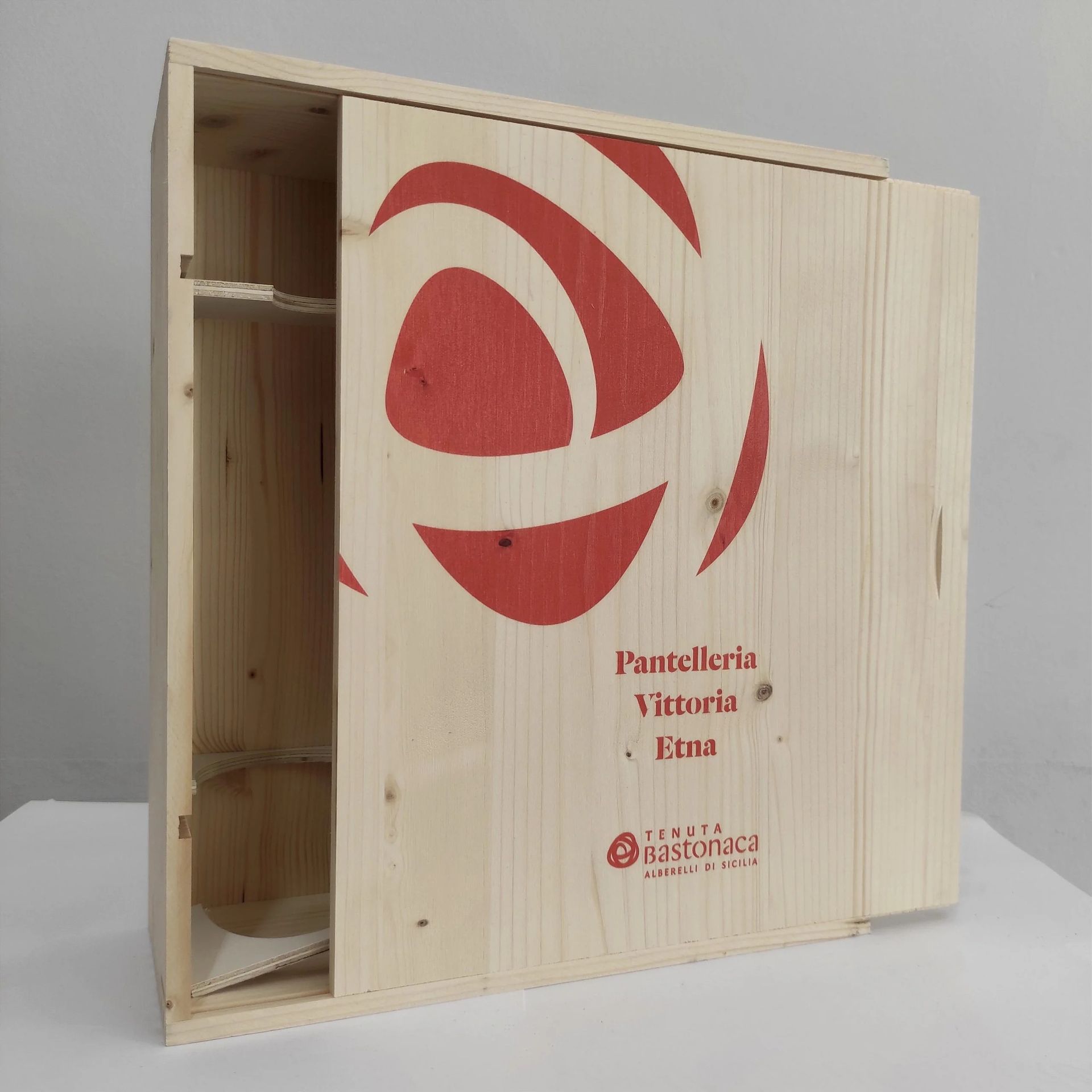 Cassa di legno con logo e testo stampati in rosso, mostrata aperta per rivelare il contenuto impilato all'interno.
