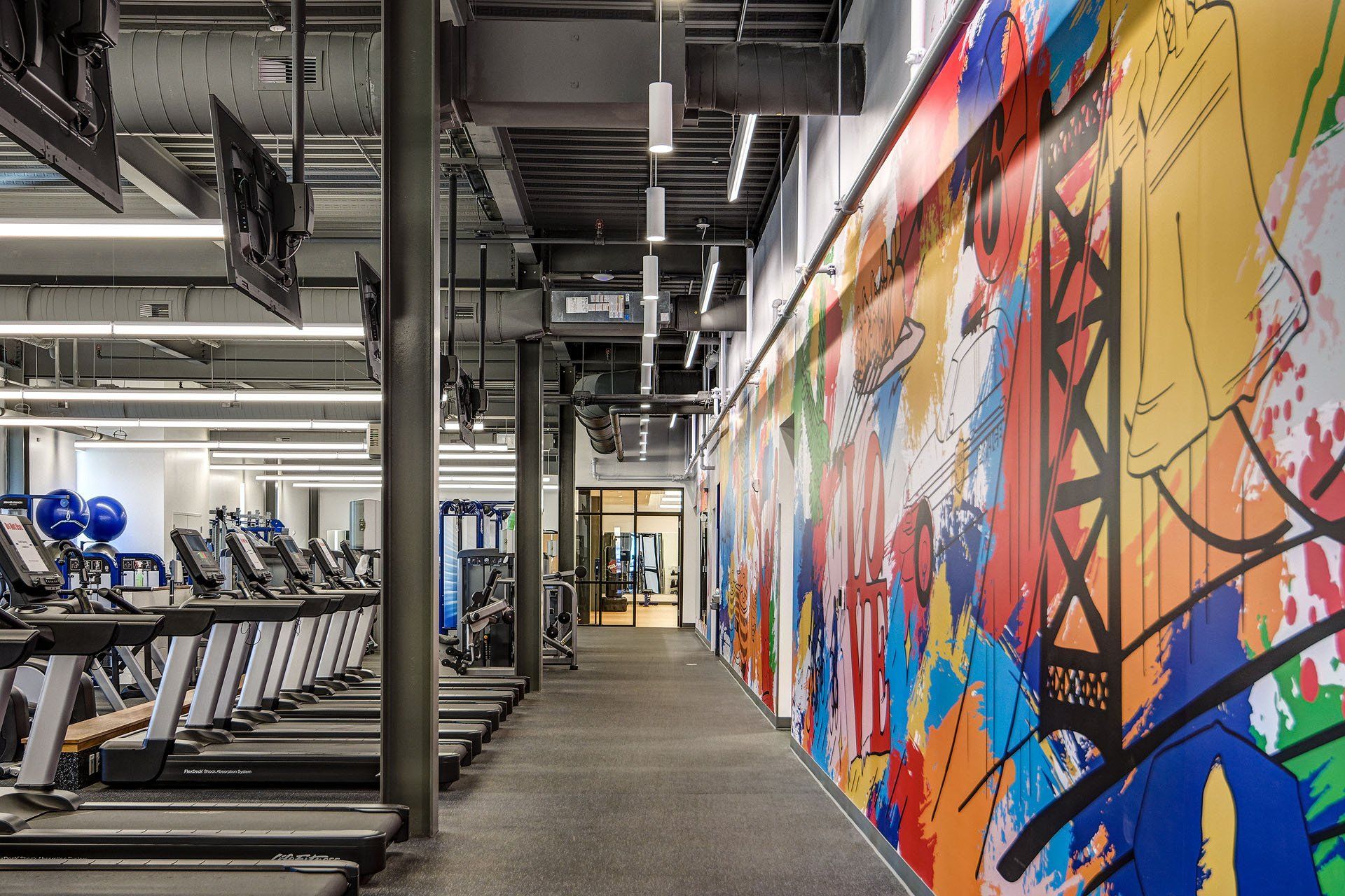 A gym with treadmills and a large mural on the wall.