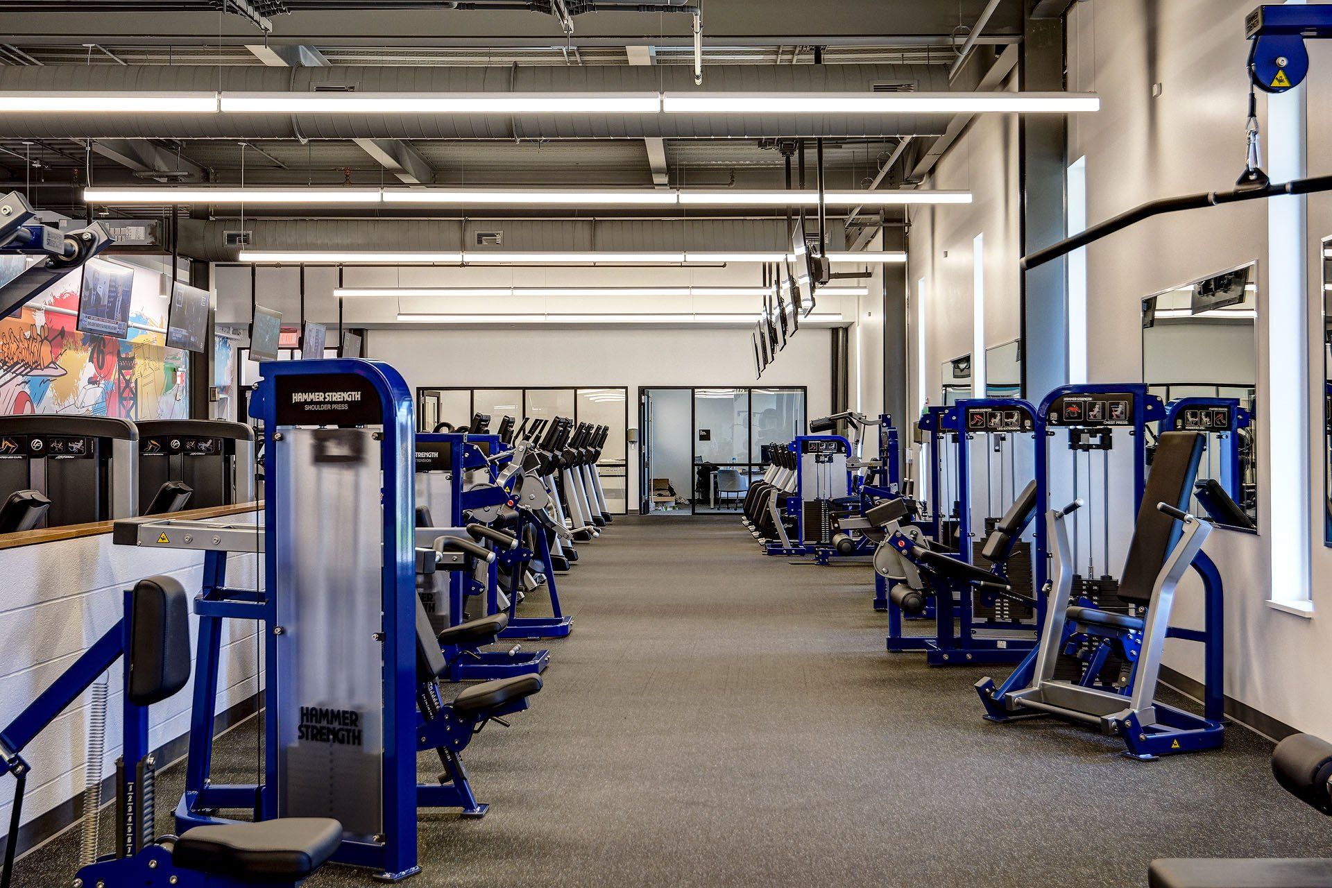 A gym filled with lots of blue and silver exercise equipment.