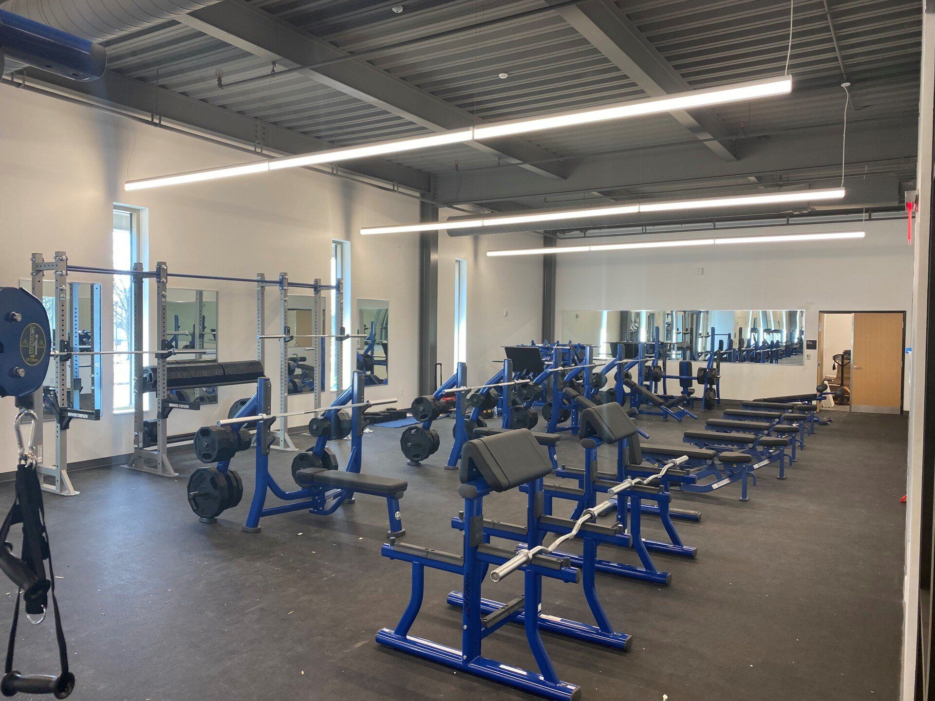 A large gym filled with lots of blue and white exercise equipment.