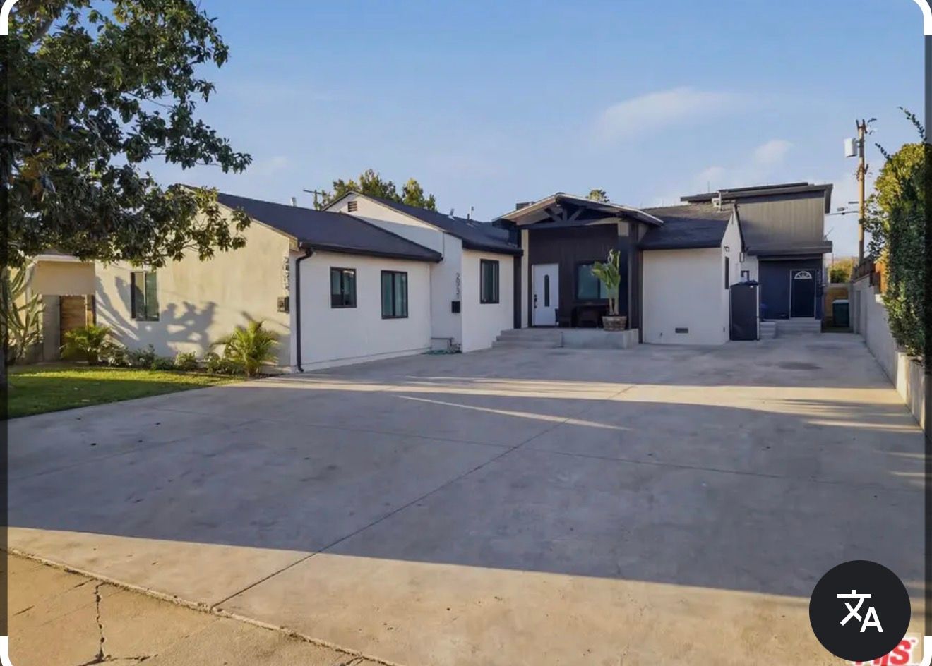 Single-story house with a large concrete driveway and a garage under a clear sky