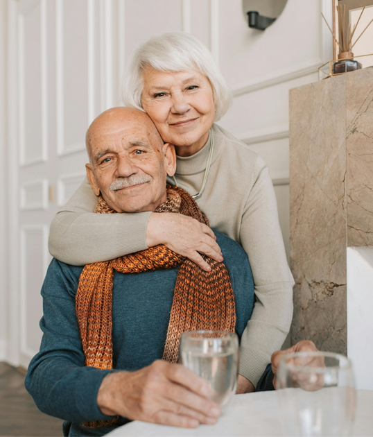 Smiling couple embracing at a table with drinks in a bright home interior