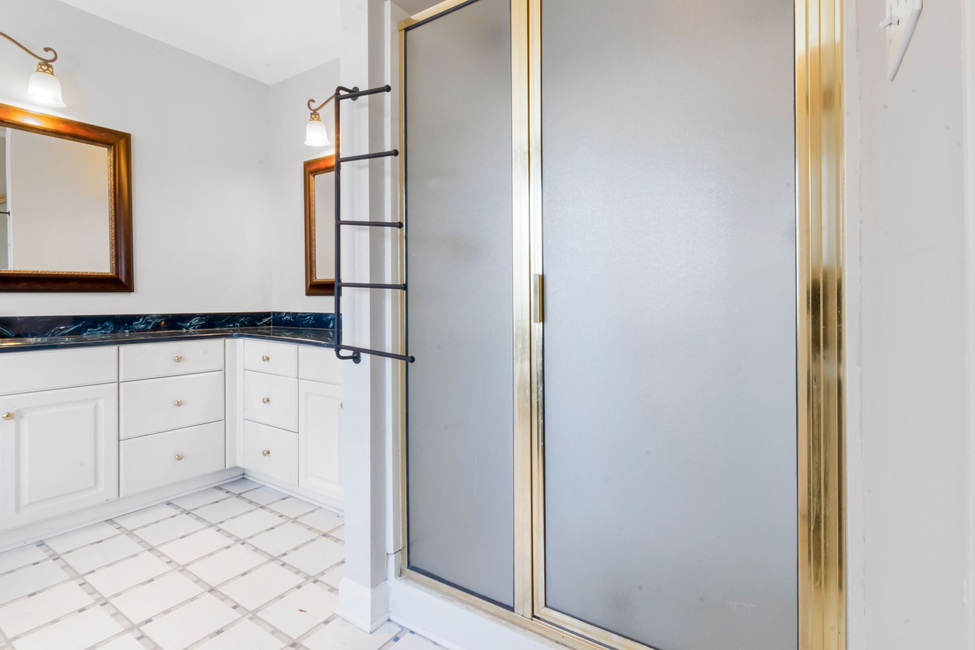 Modern bathroom with double vanity, large mirror, and frosted glass shower enclosure
