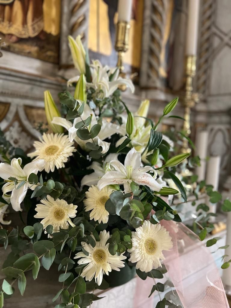 Composizione floreale con gigli bianchi e gerbere su un altare.