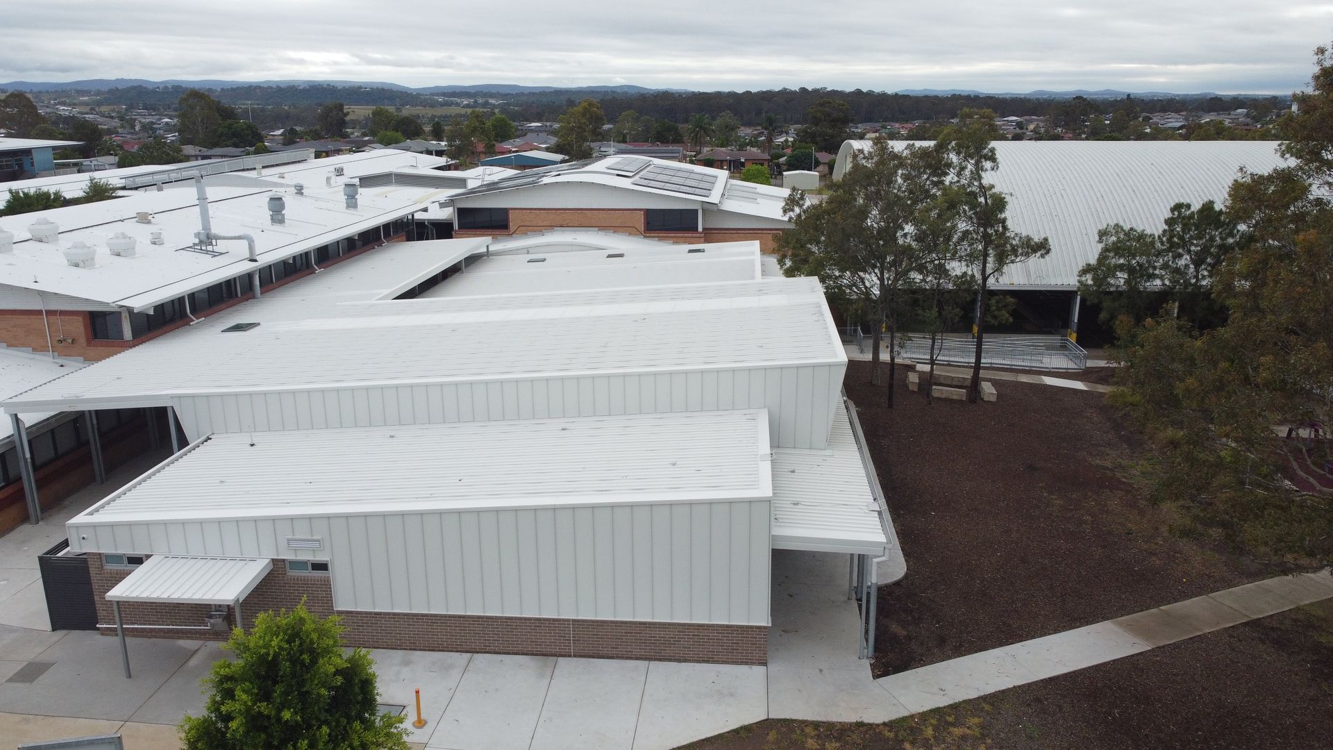 An aerial view of a school building with a white roof.
