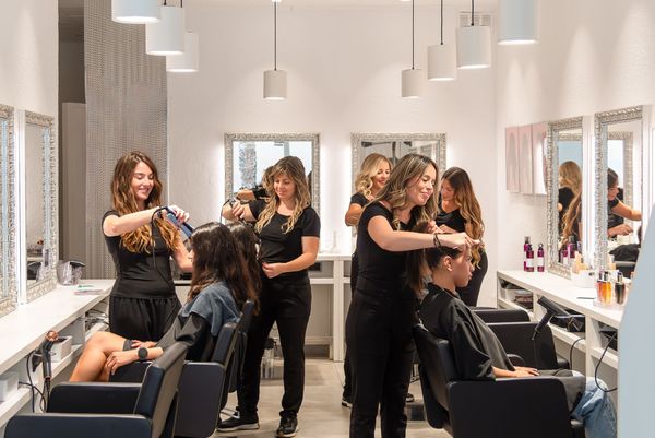 Hairdressers styling clients' hair in a modern salon.