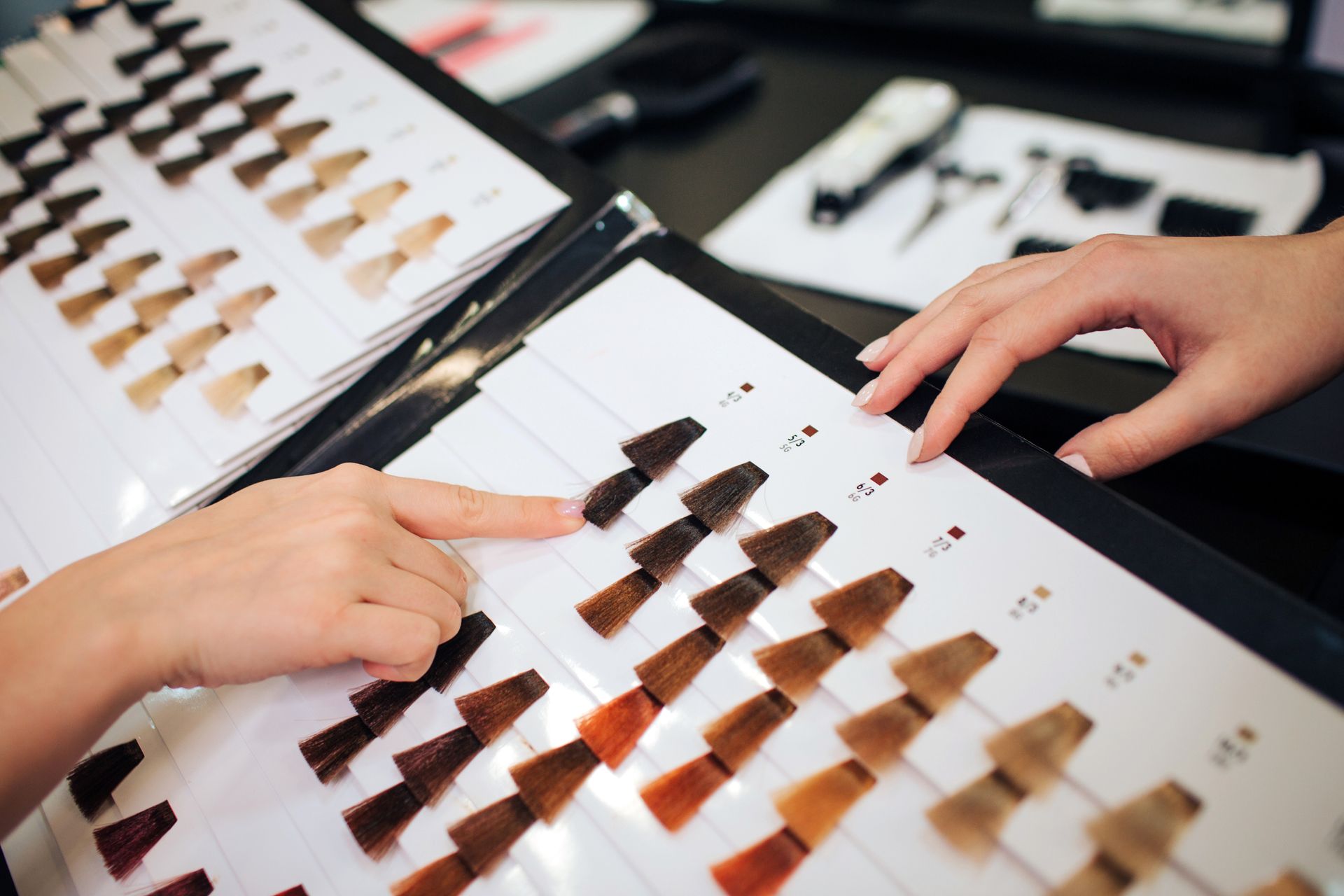 Two hands selecting hair color samples from a color swatch book used for hair dyeing. Two hands selecting hair color samples from a color swatch book used for hair dyeing.