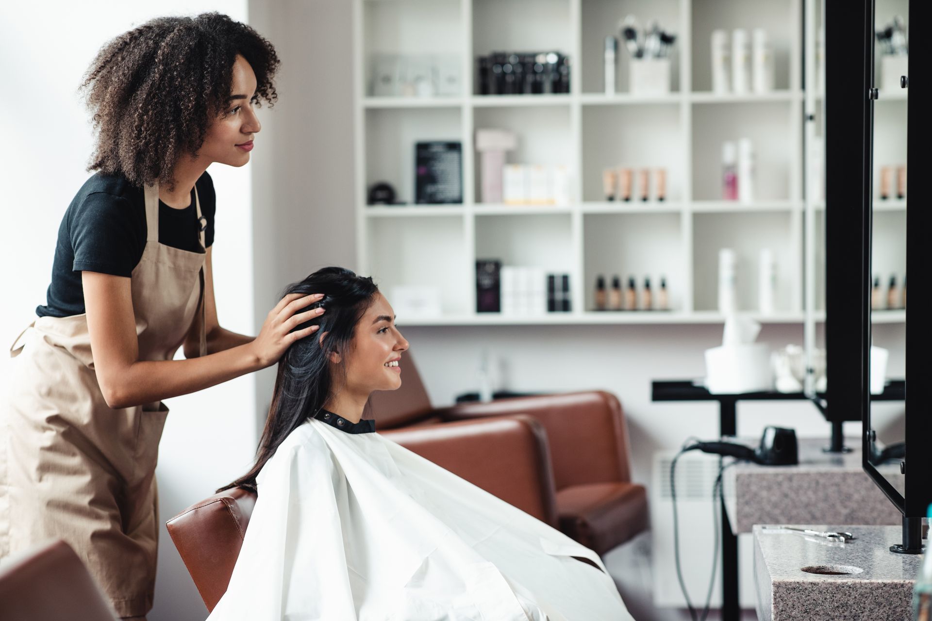 Hair stylist assisting a smiling client in a modern beauty salon.