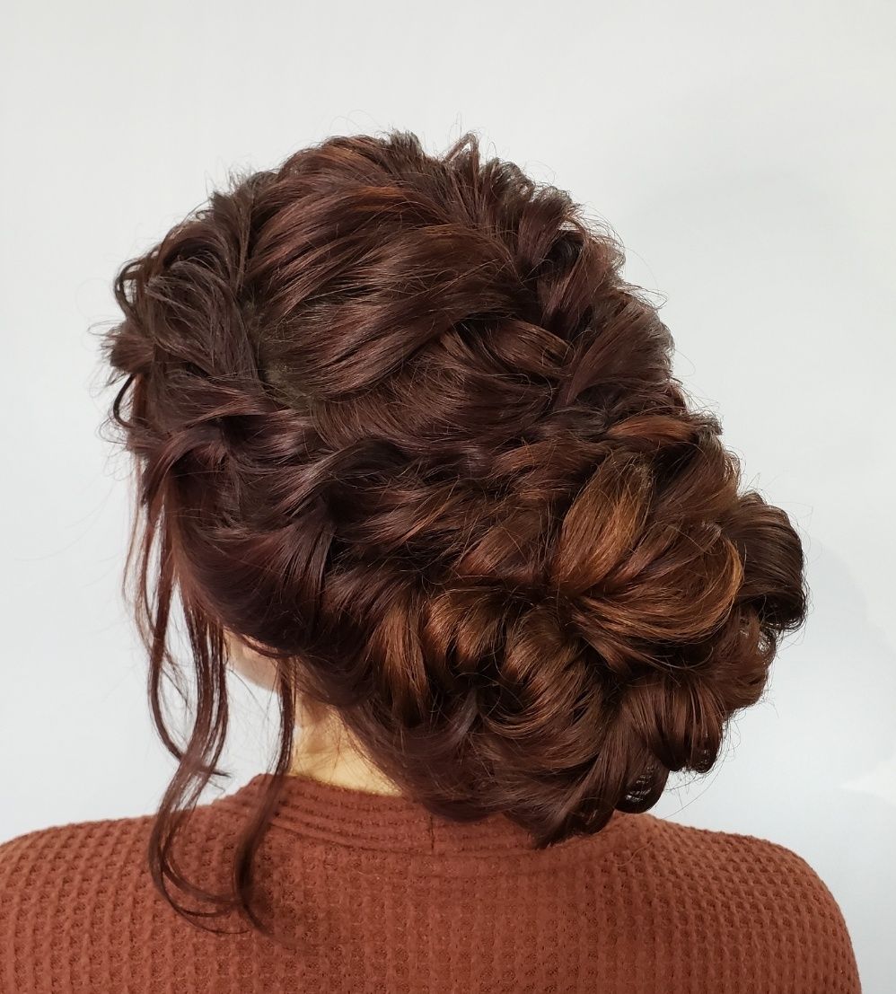 Woman with auburn hair in an updo, wearing a brown sweater, against a white background.