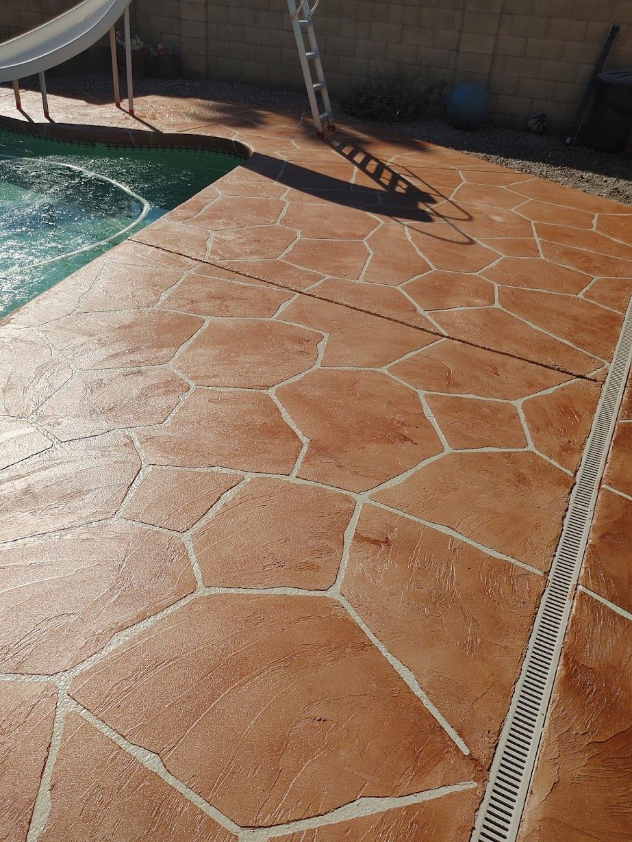 Stamped concrete patio in a reddish-brown color, around a pool.