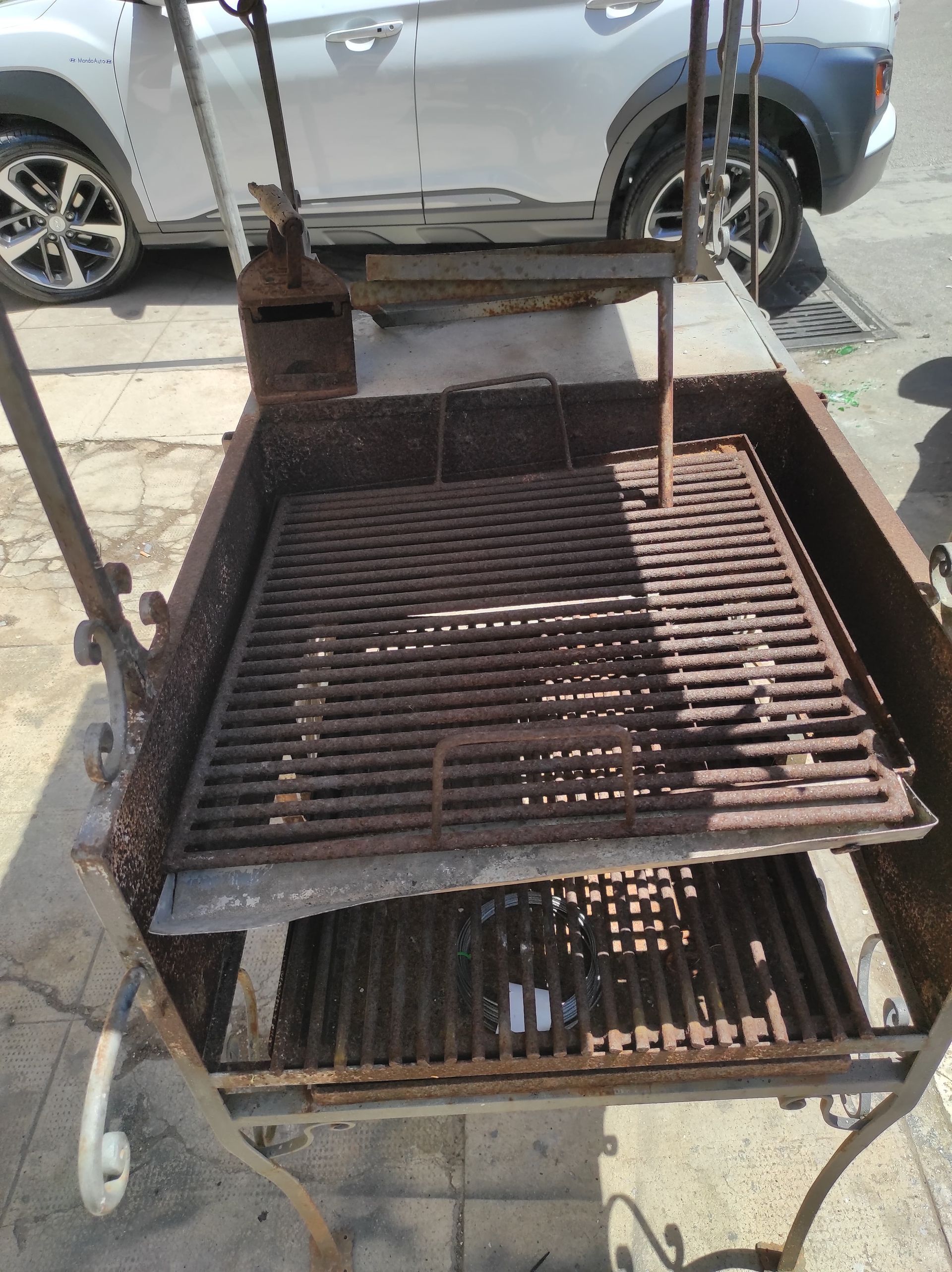 Barbecue in metallo arrugginito con due griglie, da esterno.