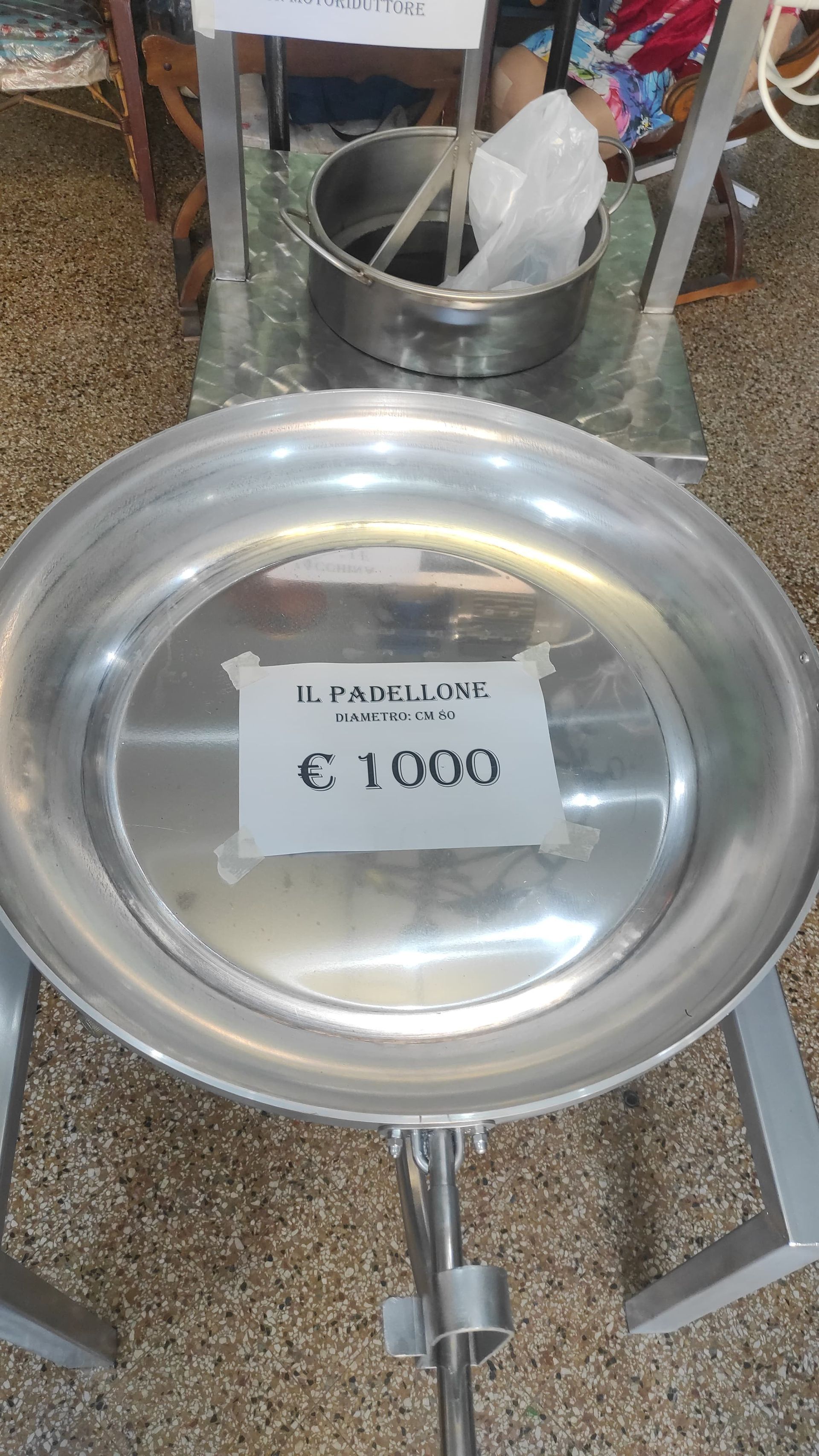 Grande padella di metallo con etichetta del prezzo di 1000 euro. Ambiente industriale.