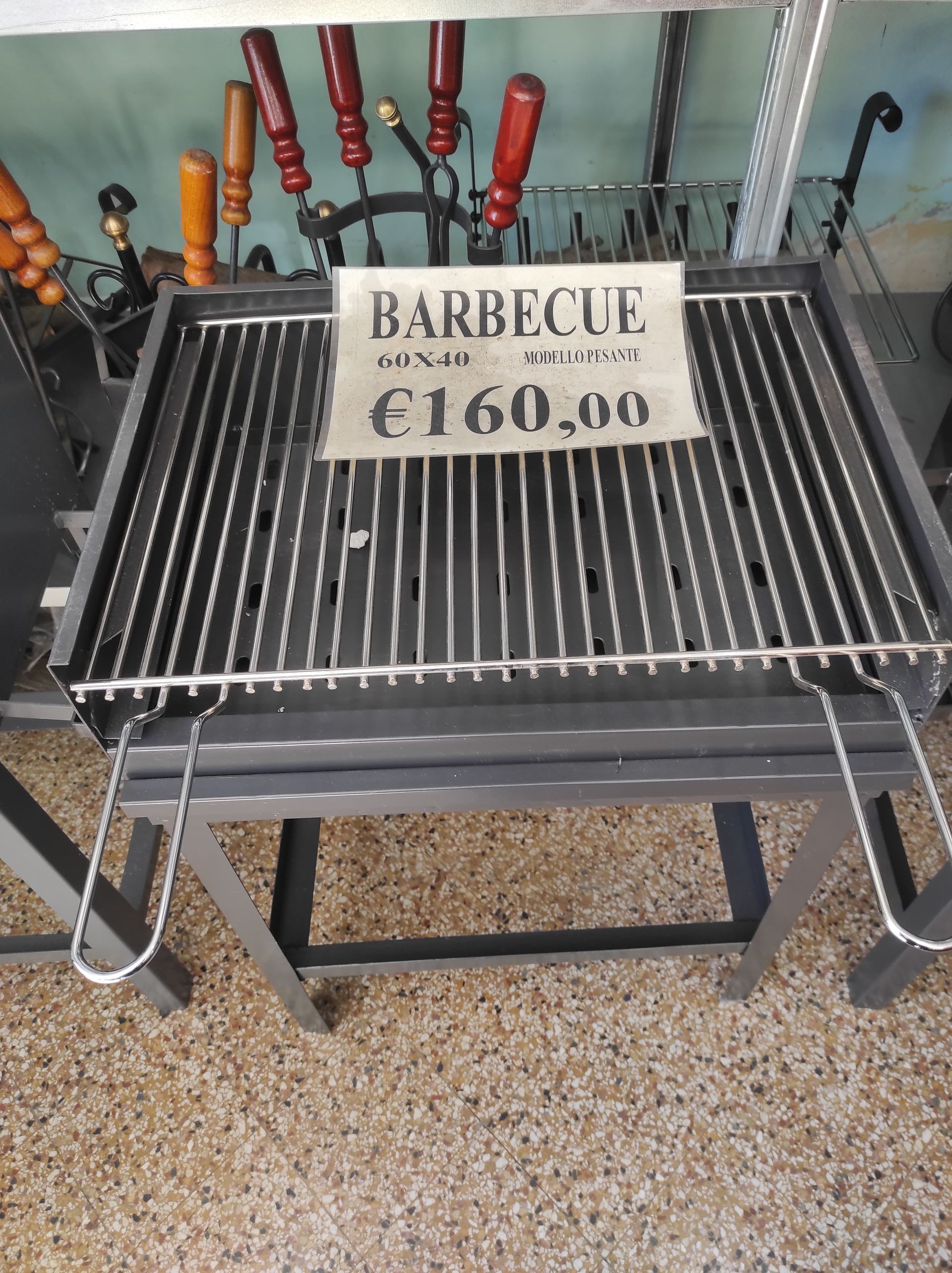 Griglia per barbecue dal prezzo di 160 €. Griglia in metallo con manici in legno in un negozio.