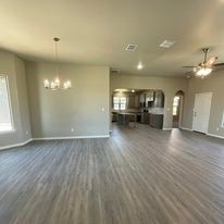An empty living room with hardwood floors and a ceiling fan.