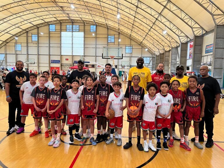 Youth basketball team and coaches posing in a gym, wearing maroon and white uniforms.