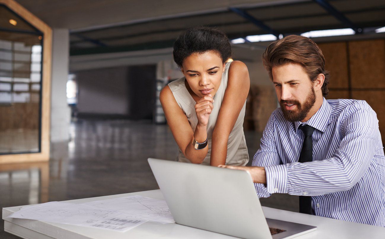 Business owners in an office using a laptop to discuss a company's website business solution.