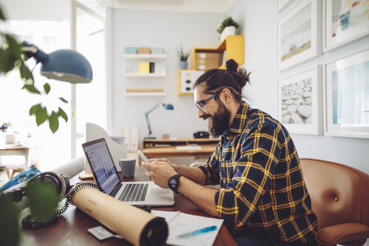 Businessman using a laptop and mobile phone to develop an effective e-commerce website for his small business.
