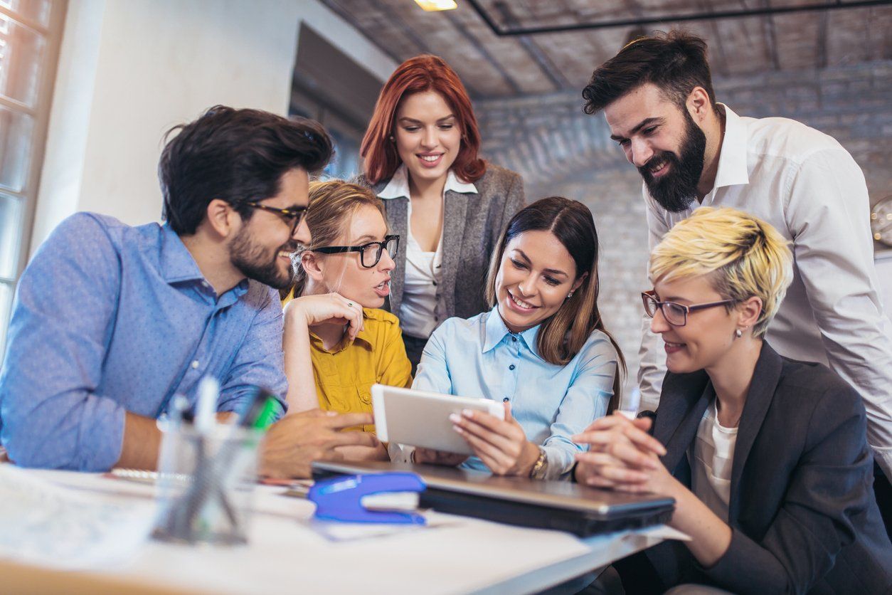 Team of sales and marketing employees in an office brainstorming about their company's digital marketing strategies.