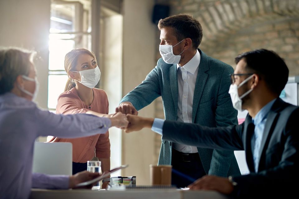 Team of business owners colliding their fists in agreement about adapting to a post-pandemic economy.