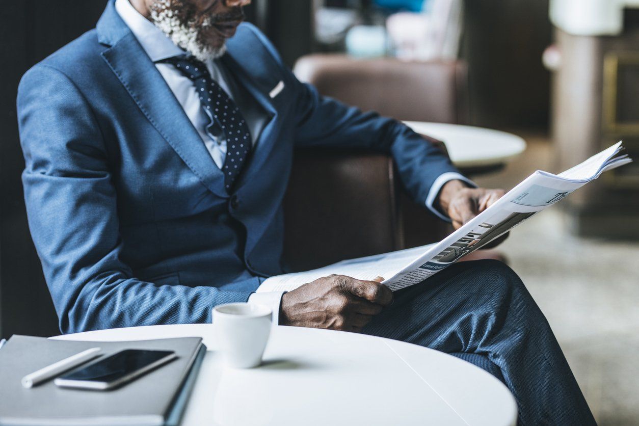 Newspaper publishers - male African-American reading a newspaper in his office.