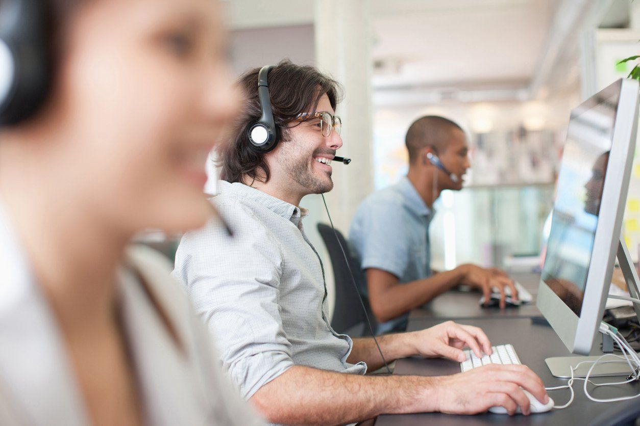 Team of outsourcing professionals wearing headsets while speaking to business customers online.