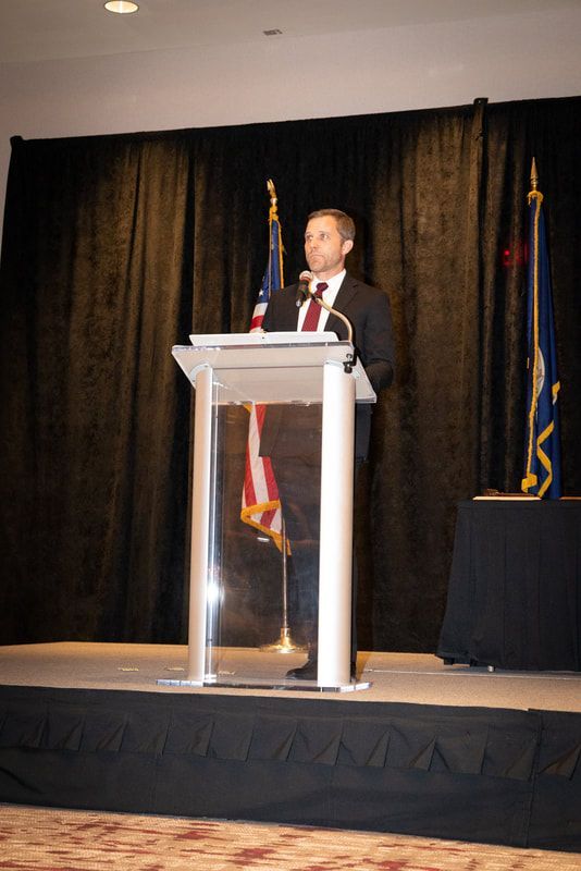 A man in a suit and tie is standing at a podium giving a speech