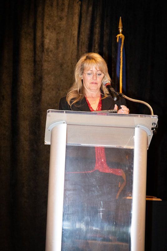 A woman is standing at a podium speaking into a microphone.