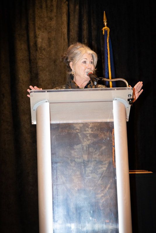 A woman is standing at a podium speaking into a microphone.