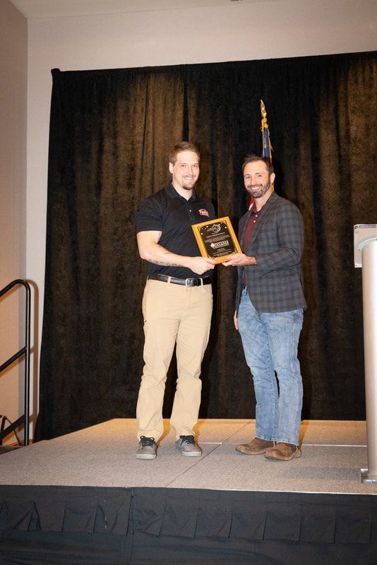 Two men are standing on a stage holding a plaque.