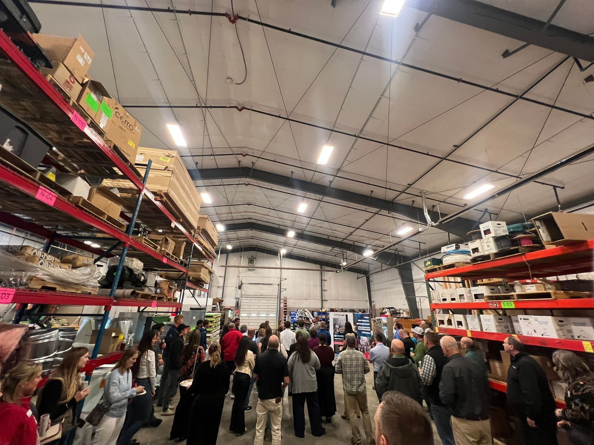 A large group of people are standing in a large warehouse.
