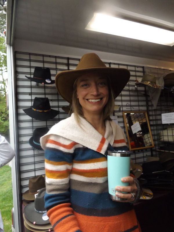A woman wearing a cowboy hat is holding a cup