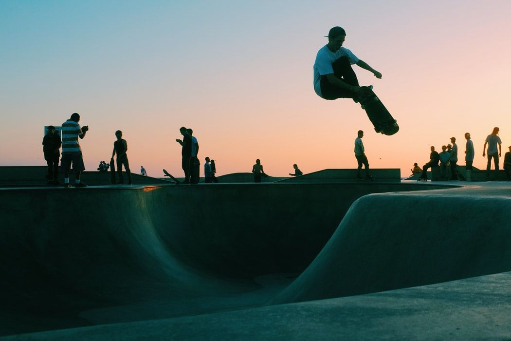 A man is jumping in the air while riding a skateboard at a skate park.