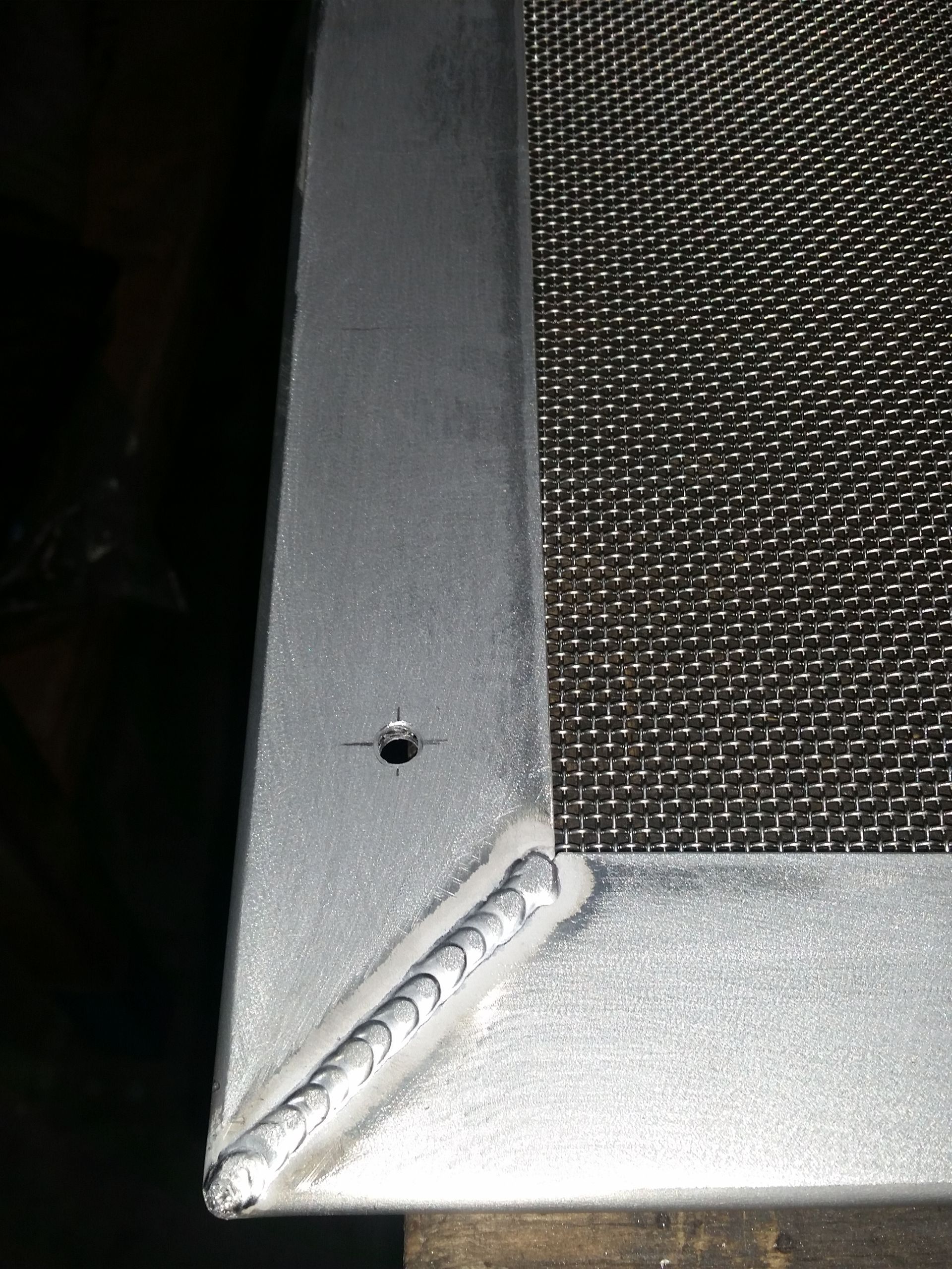 A close up of a metal screen with a hole in the middle.