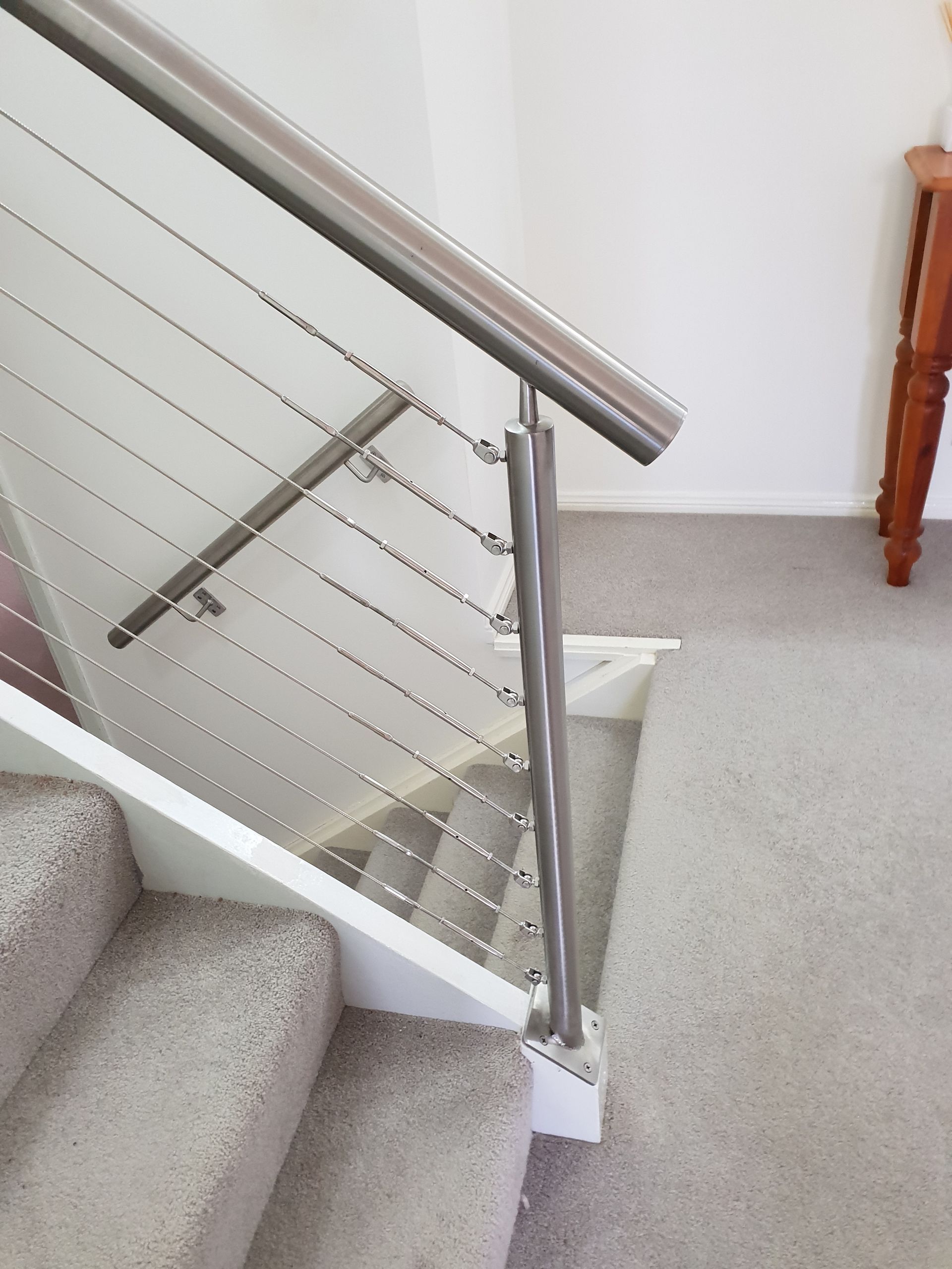 A staircase with a stainless steel railing and carpeted steps