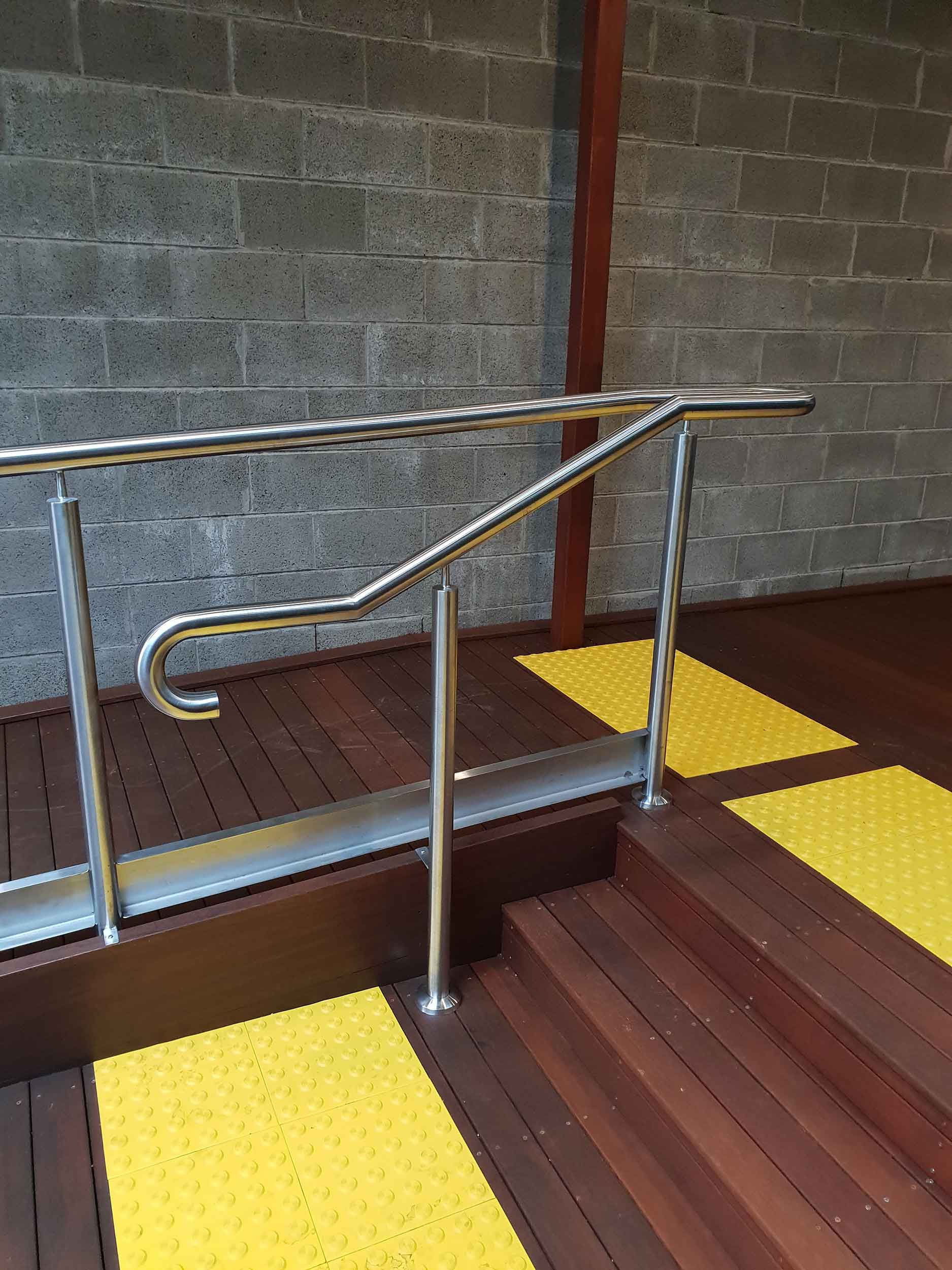 A wooden deck with a stainless steel railing and yellow steps.