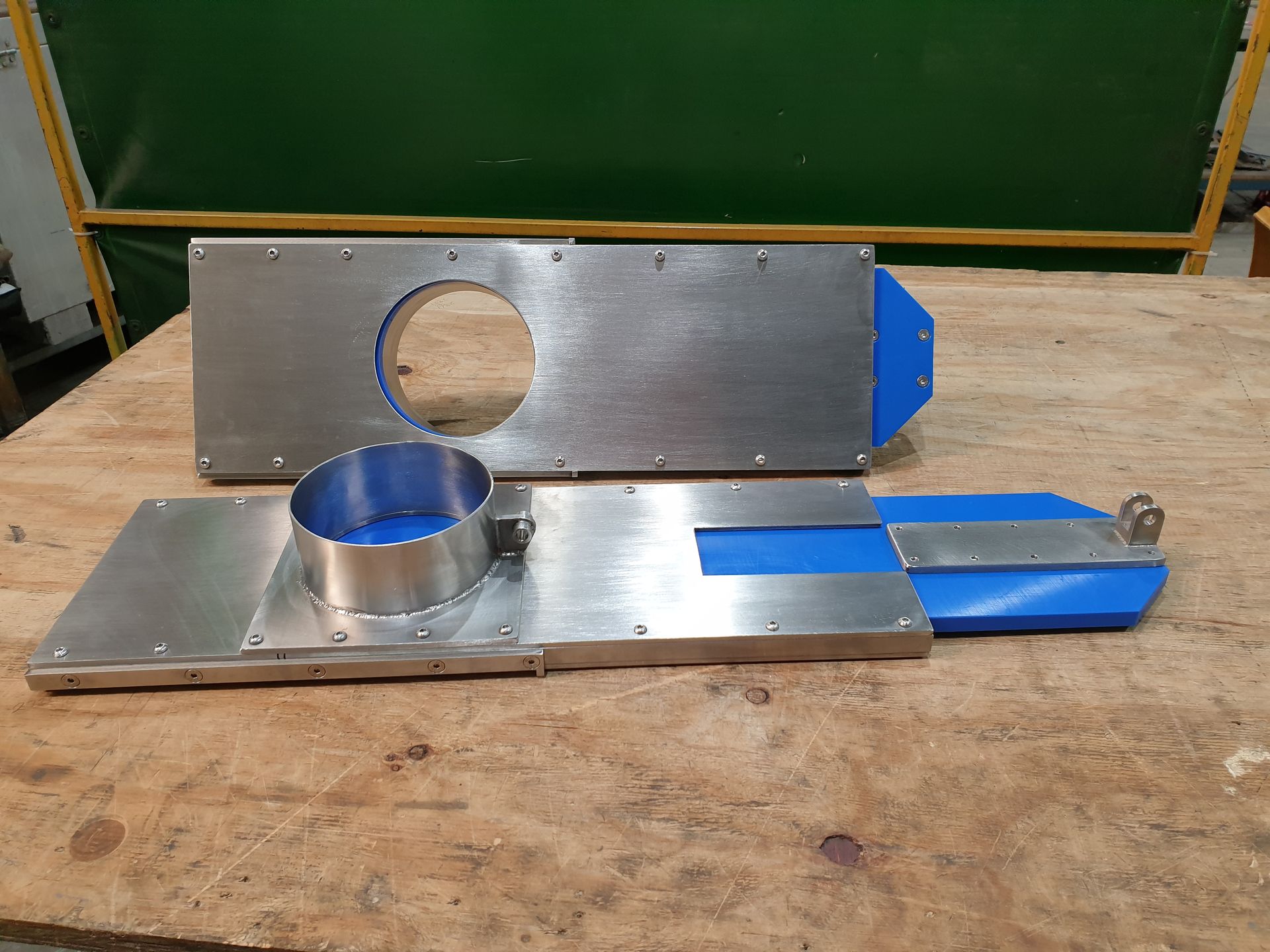 A metal object with a blue handle is sitting on a wooden table.