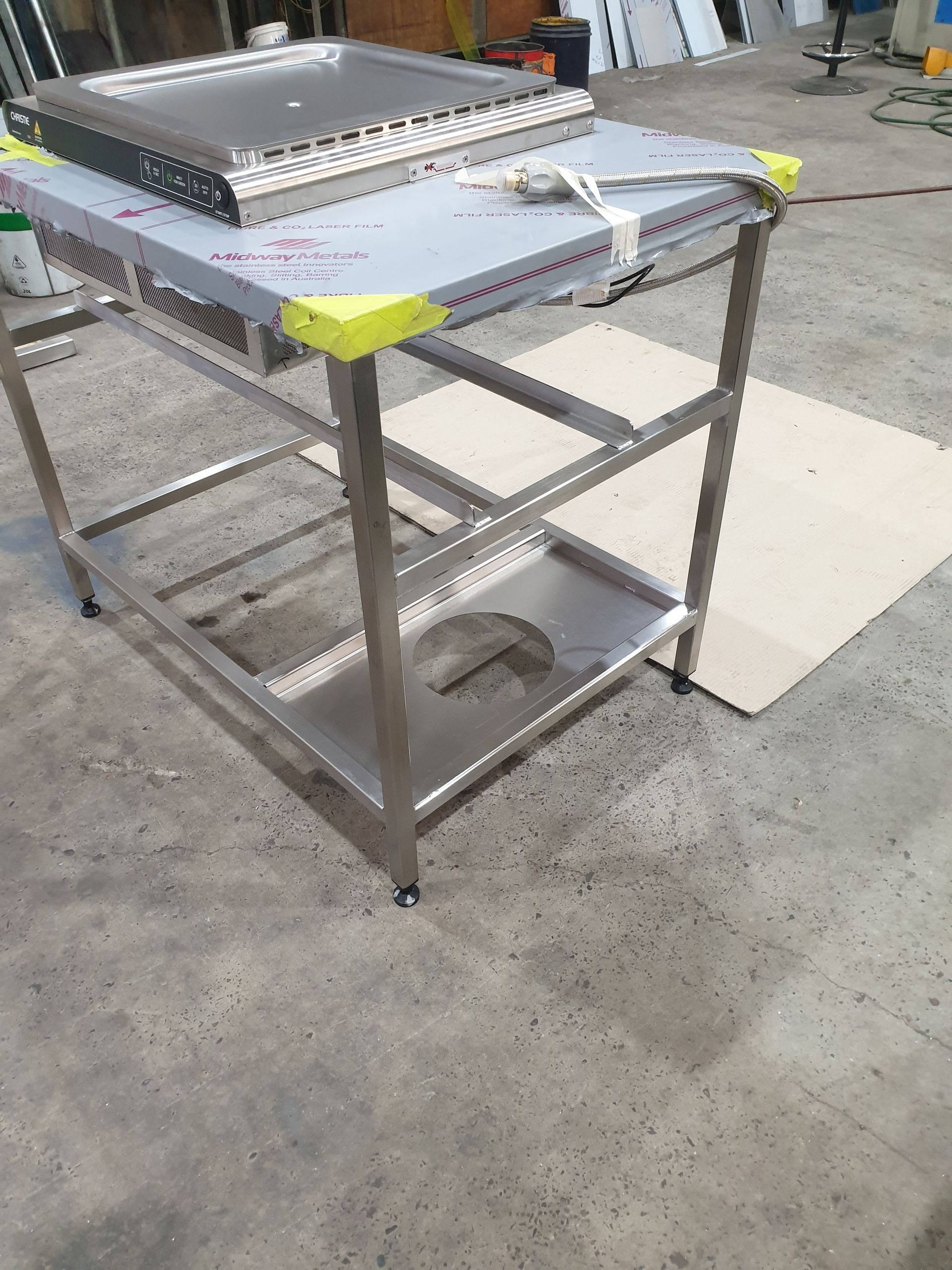 A stainless steel table is sitting on top of a concrete floor.